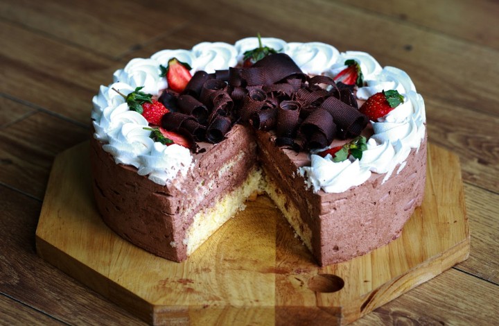 Čokoladna torta lepo ukrašena šlagom i jagodama